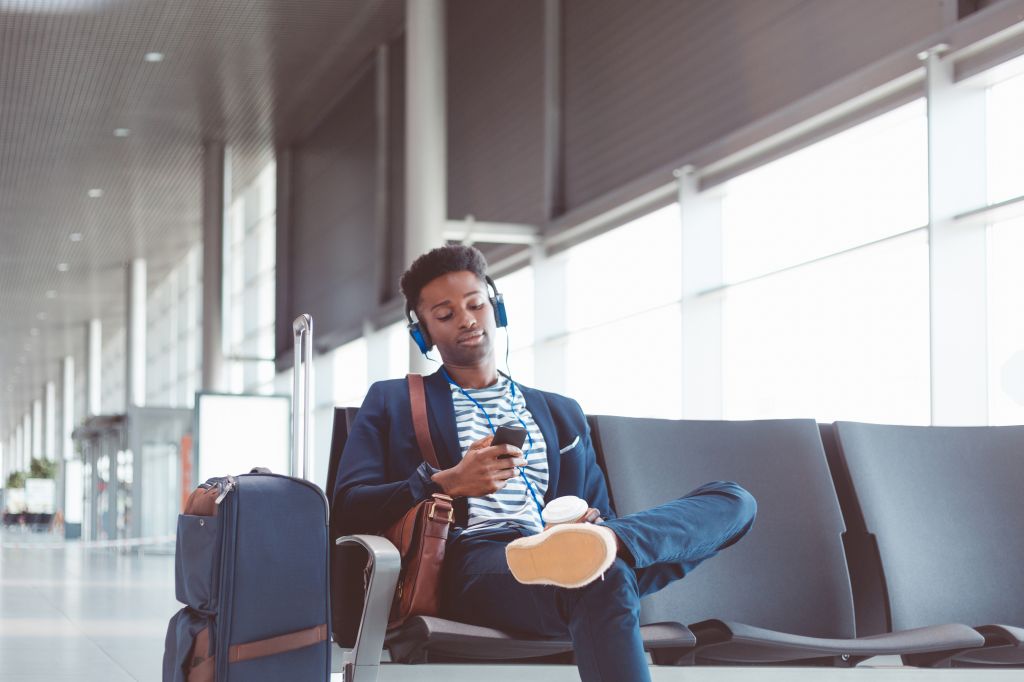 Young african man waiting for flight at airport lounge