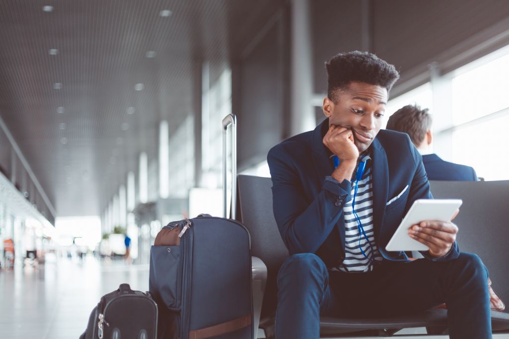 Young man at airport waiting lounge using digital tablet