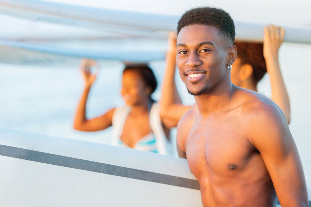Handsome African American teenage boy with surfboard