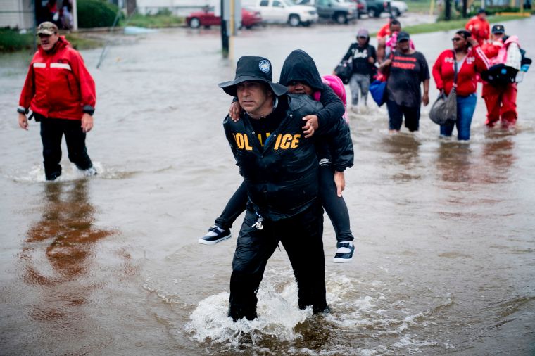 A police officer carries a child to safety.