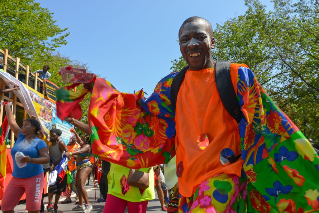 A brightly-colored dancer struts in the parade. Massive...