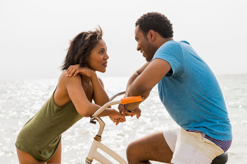 Couple talking on beach with bicycle