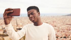 Man taking selfie through smart phone against city