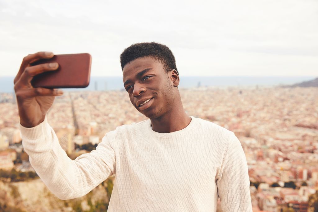 Man taking selfie through smart phone against city