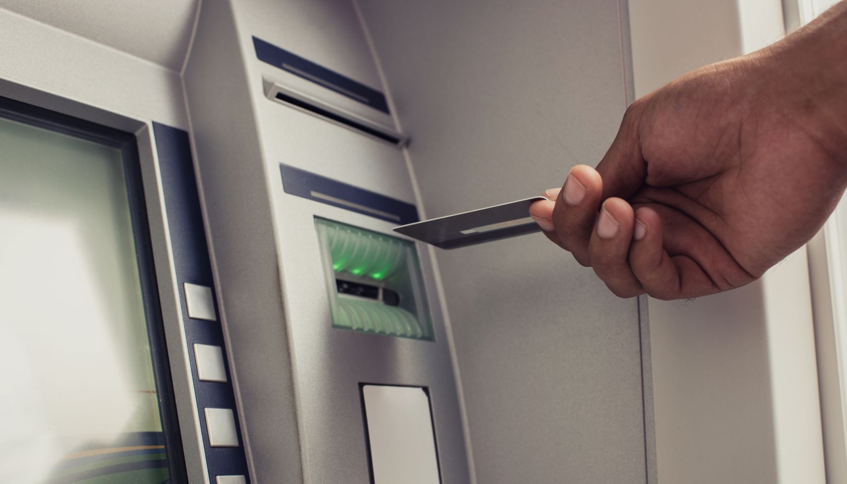 Close up of unrecognizable person with credit card on ATM.