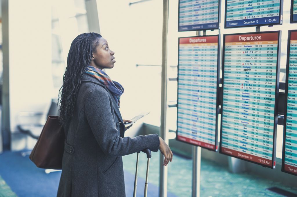 Young woman at airport checking departures board.