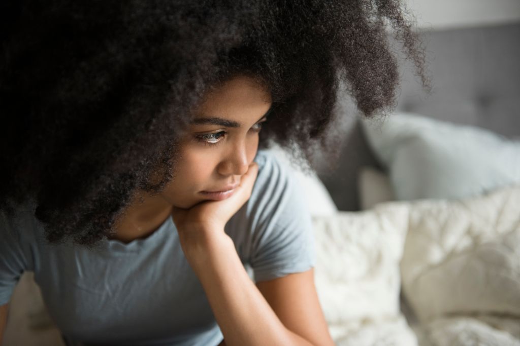 Unhappy African American woman sitting in bed