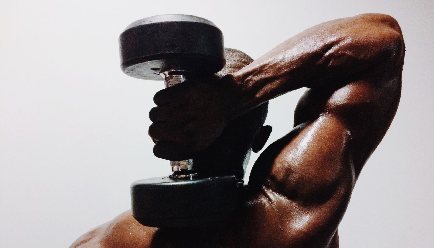 Shirtless Man Holding Dumbbell Against White Background