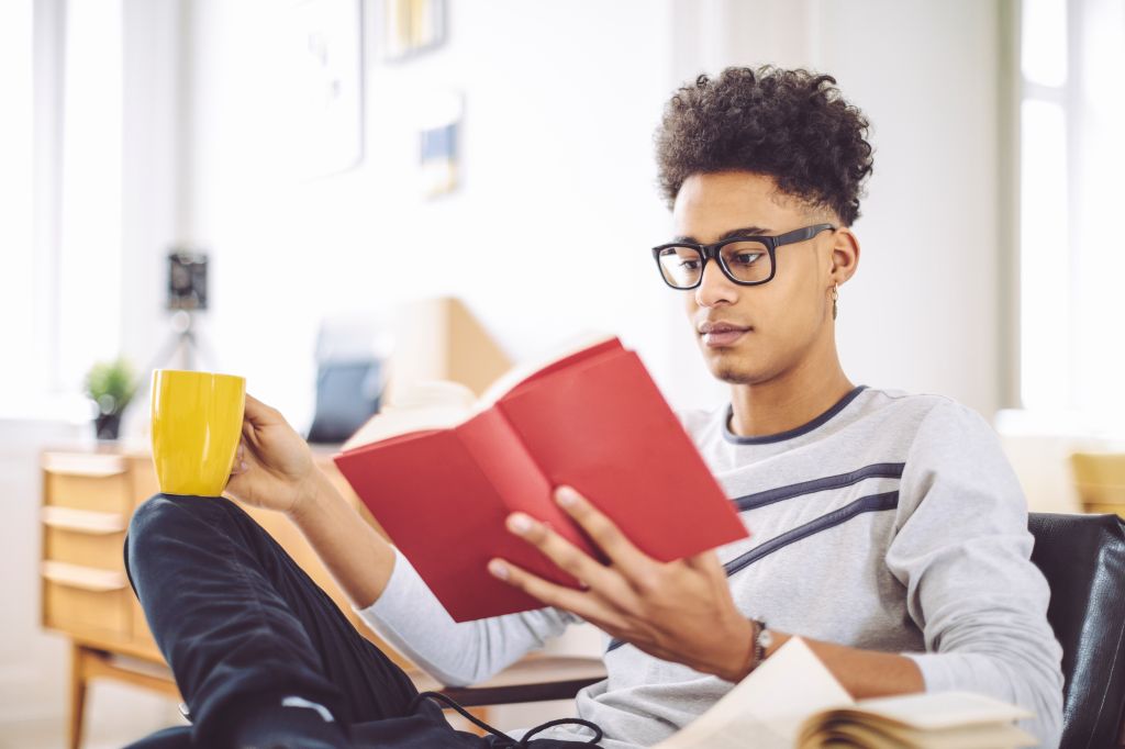 Young man reading a book at home