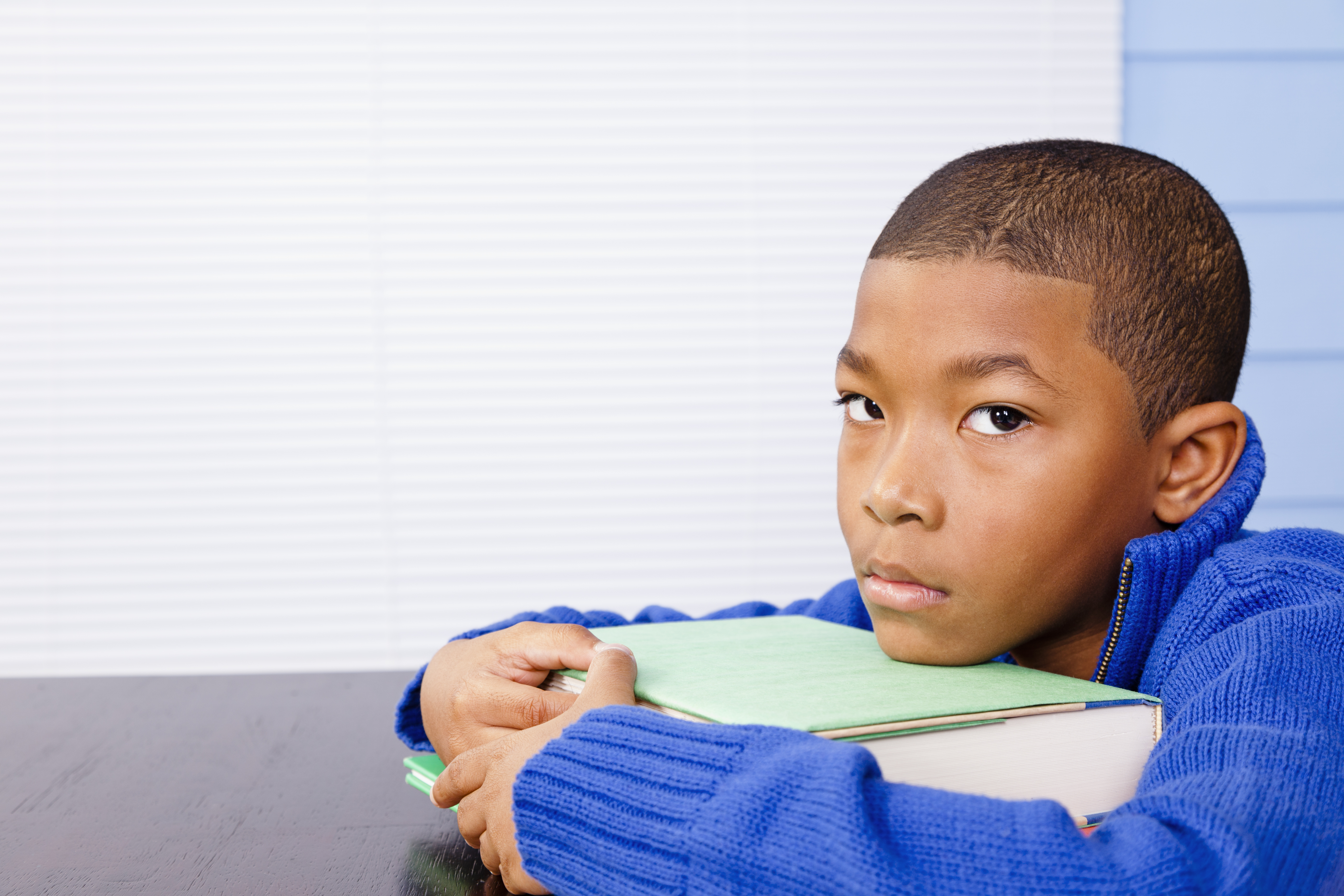 Young elementary aged boy procrastinating homework or depressed