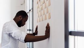 Man leaning against wall with adhesive notes in office