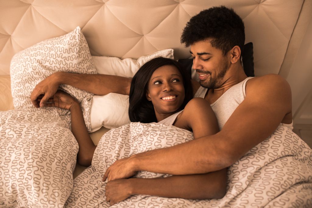 Young loving black couple lying in the bed and communicating.