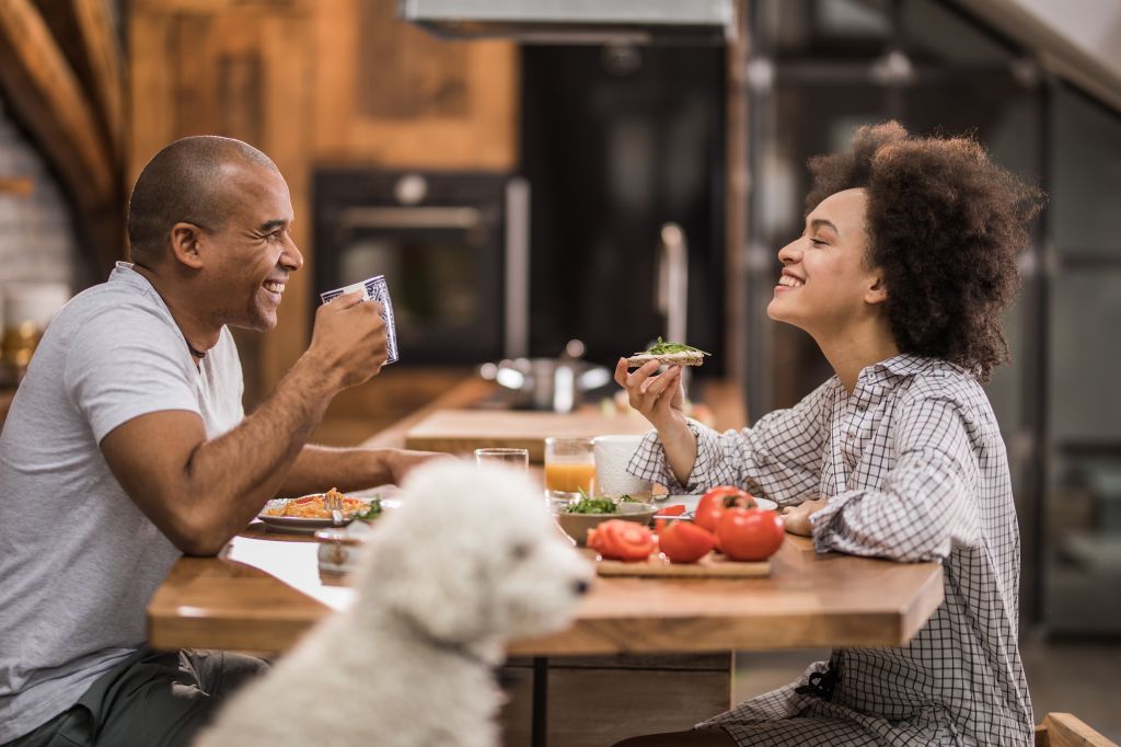 Happy black couple enjoying in conversation during breakfast time in the kitchen.