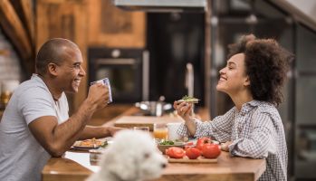 Happy black couple enjoying in conversation during breakfast time in the kitchen.