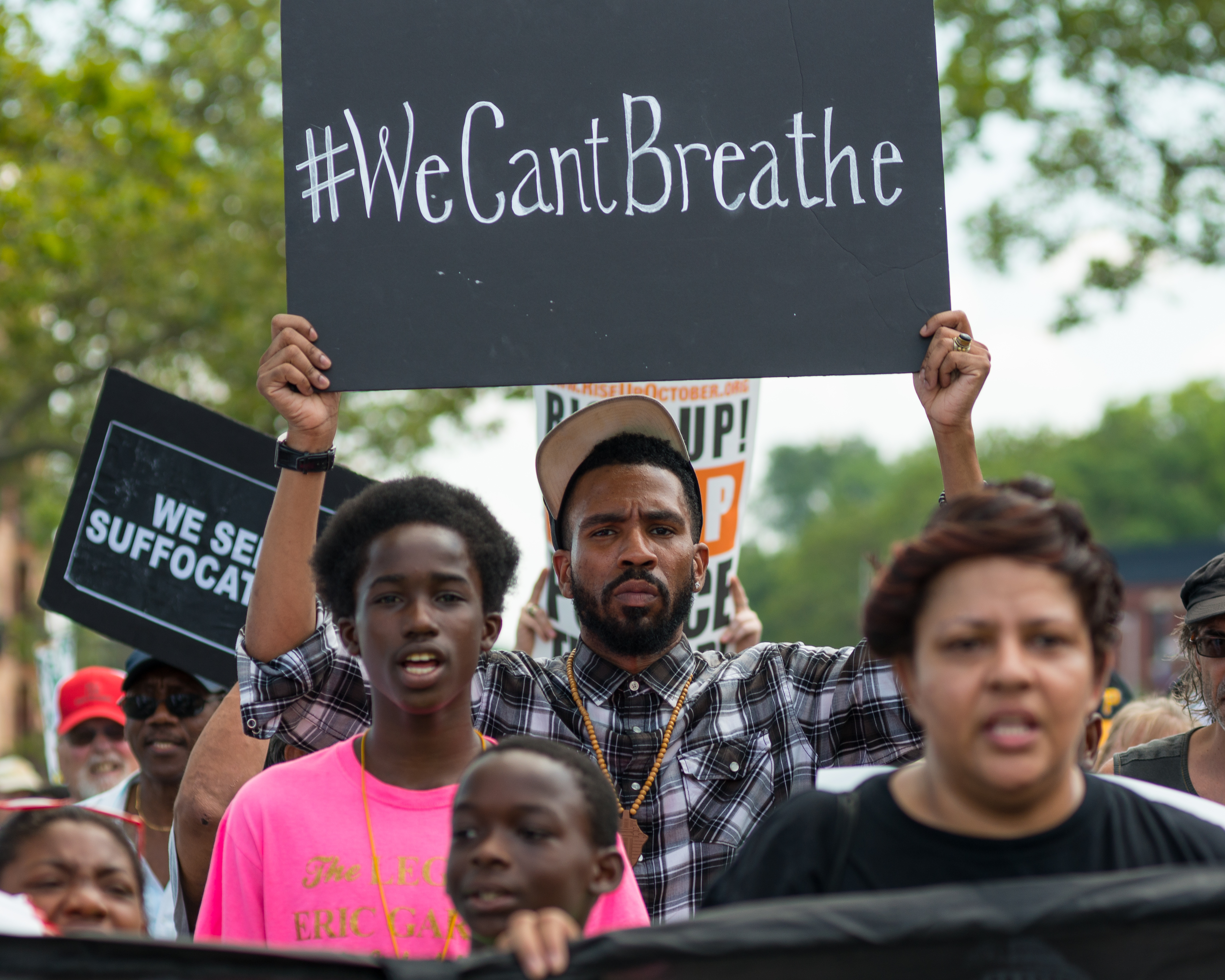 Rally participants hold signs while marching on Bay Street.