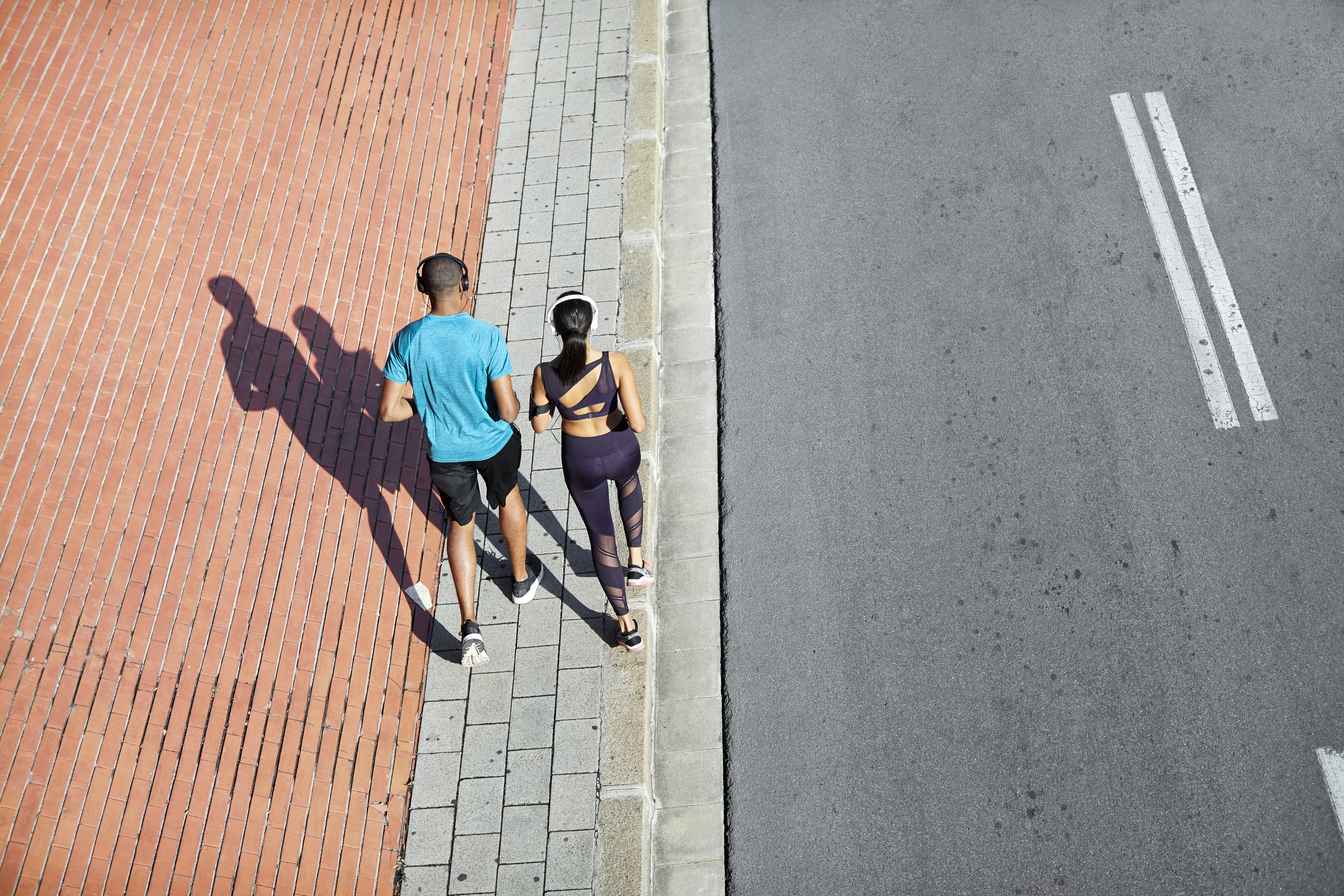 High angle view of couple jogging on sidewalk