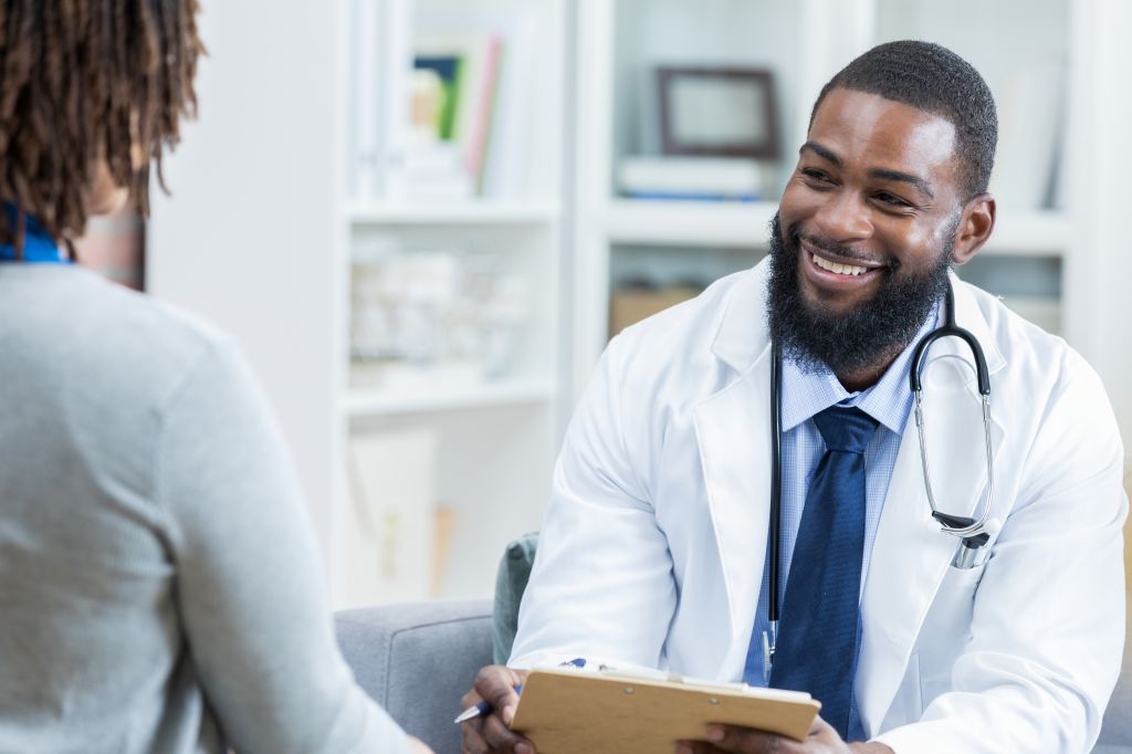 Physician takes notes while talking with patient