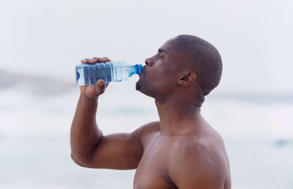 Side profile of a young man drinking water from a bottle