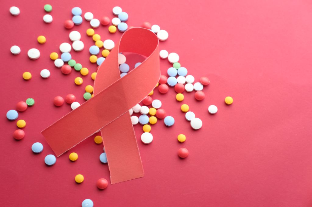 Red Ribbon and Medicins - AIDS awareness symbol on the red background.