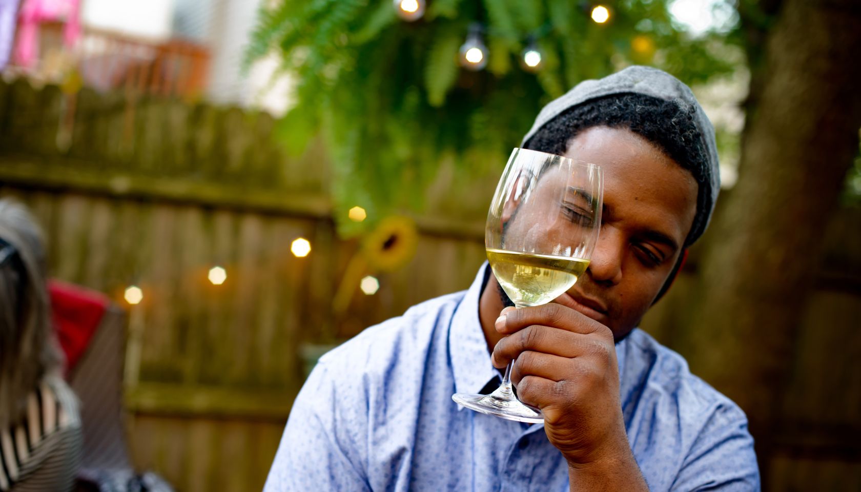 Man at garden party, holding wine glass, inspecting wine