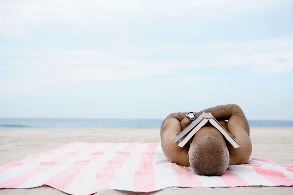 Man sleeping on beach with book on his face