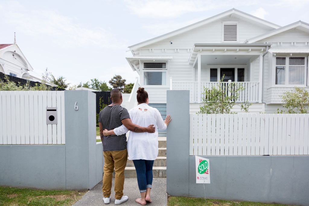 Couple outside house with sold sign
