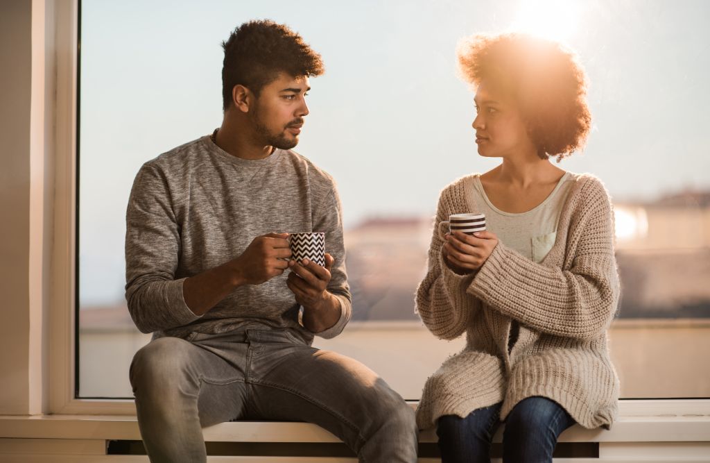 Young black couple talking to each other during coffee time.