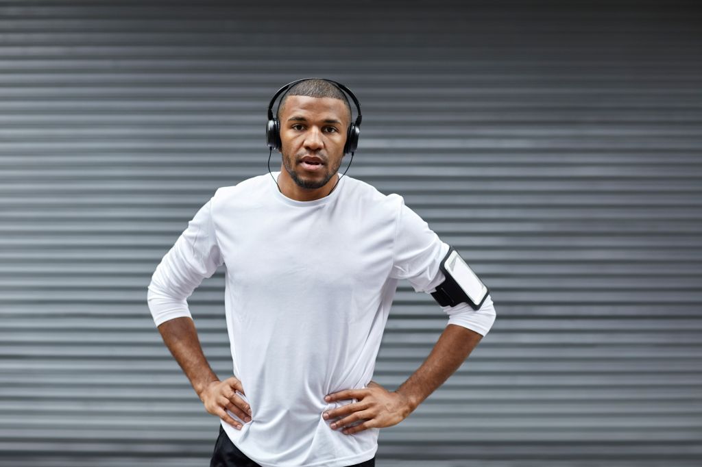 Sporty man with hands on hips against shutter