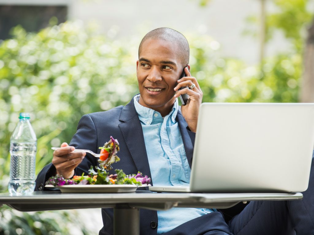Black businessman working and eating lunch outdoors