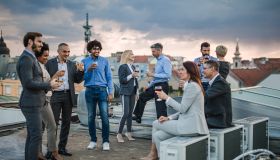 Large group of happy business colleagues talking on a rooftop party.