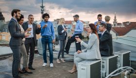 Large group of happy business colleagues talking on a rooftop party.