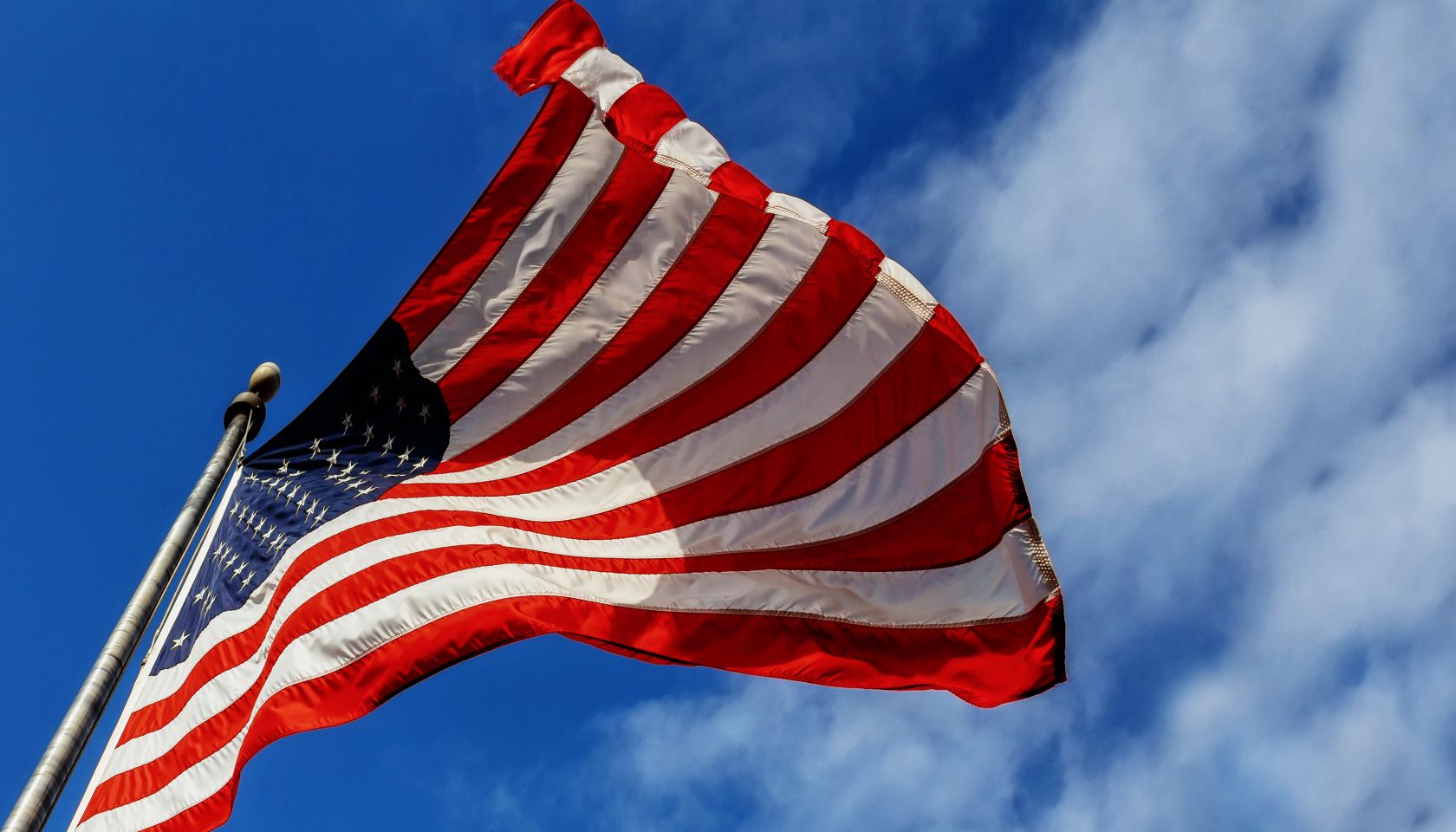 Low Angle View Of American Flag Waving Against Sky