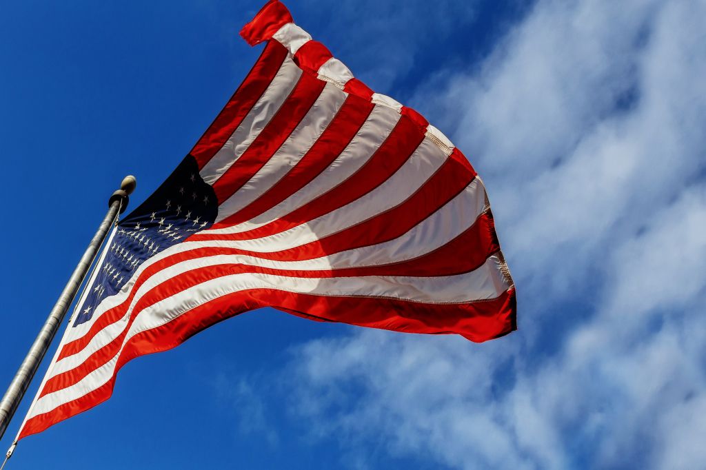 Low Angle View Of American Flag Waving Against Sky
