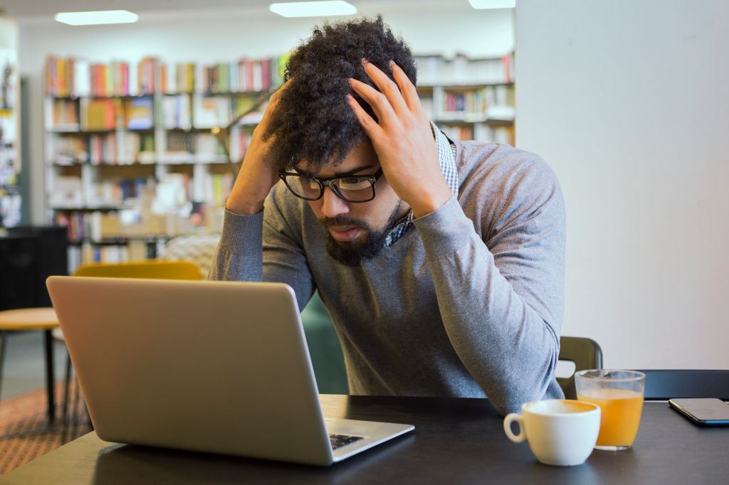 Young student getting frustrated over laptop in library