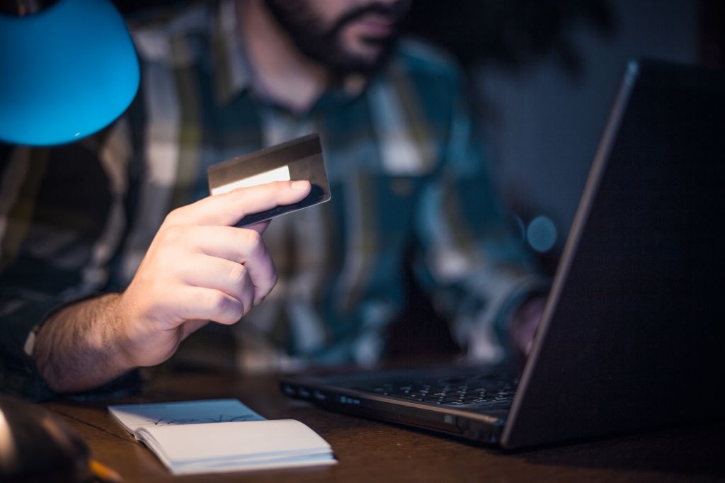 Close-up of a man using credit card to shop from home