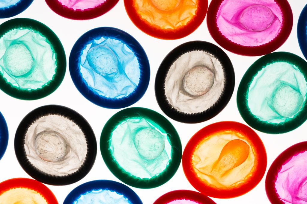 Close-Up Of Colorful Condoms Arranged Over White Background