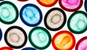 Close-Up Of Colorful Condoms Arranged Over White Background