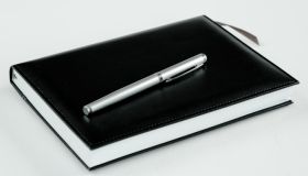 High Angle View Of Book With Pen On White Background