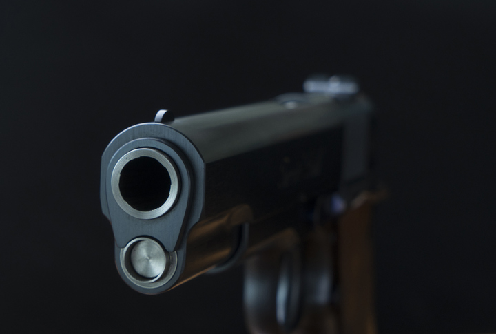 close up pistol gun barrel and wooden and dark black ground