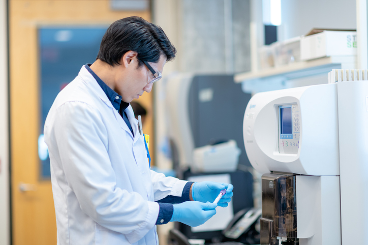 Asian Scientist Checking a Vial Before Processing it in the Equipment stock photo