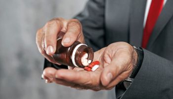 Businessman holding pills in open hand
