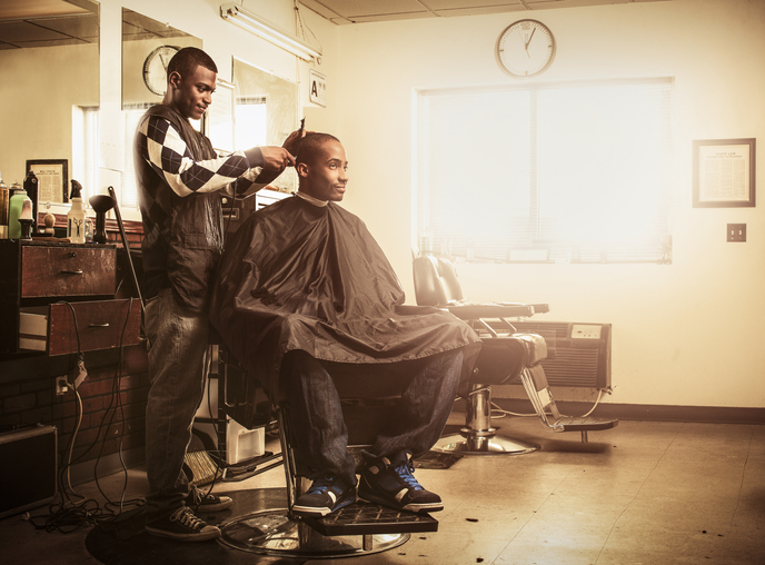 Barber in traditional barber shop shaving man's head