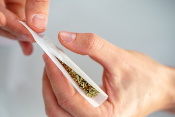 High Angle View Close-up of Young Adult Man Rolling a Marijuana Joint on Gray Background