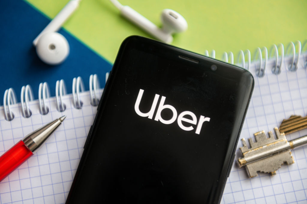 In this photo illustration, a Uber logo seen displayed on a...