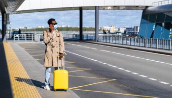 Man With Suitcase Talking Over Phone While Standing On Road At Airport