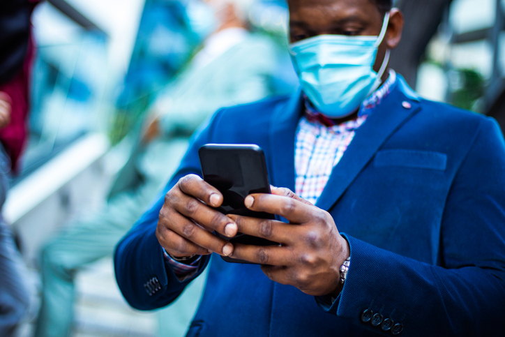 Three business men outside. Man using mobile phone. Focus is on hands.