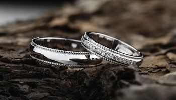 Pair of stylish silver wedding rings on wood background