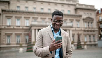 Happy young African American businessman using a smart phone