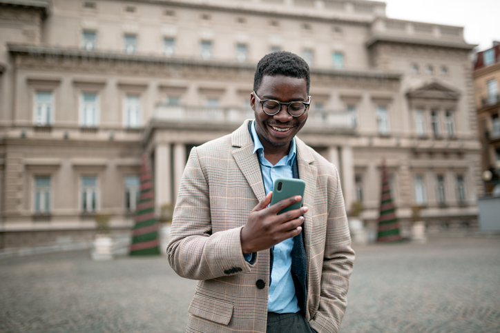 Happy young African American businessman using a smart phone