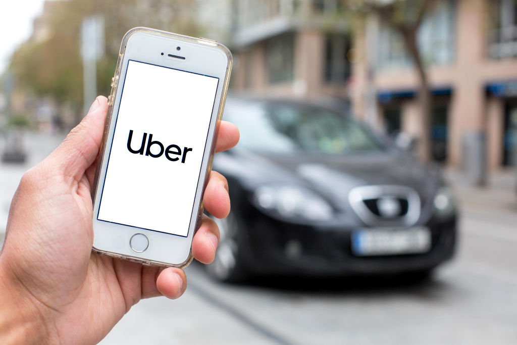 In this photo illustration a Uber logo seen displayed on a...